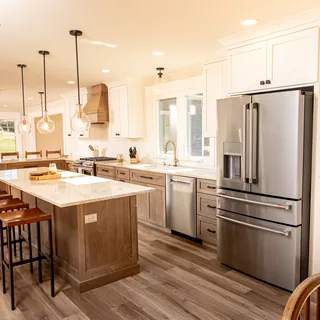 Custom kitchen island with stainless steel refrigerator and pendant lighting