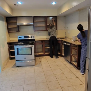 Two workers removing original dark wood cabinet doors and carcasses during kitchen demolition in Downingtown, PA