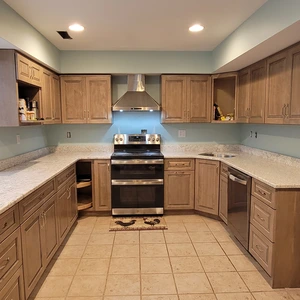 Near-complete kitchen with light-stained cabinets, granite countertops, and stainless range hood installed