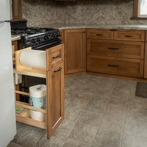 Slim pull-out pantry organizer beside gas range with paper towels and supplies in Willow Street, PA kitchen